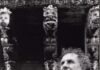 Angelo Scandurra ripreso di profilo, mezzo busto, capelli folti e ricci. Sullo sfondo i capitelli di un edificio barocco