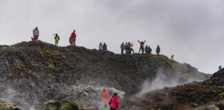 Tourists in a wild landscape shrouded in the fog. Some of them take pictures and selfies