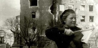 in this black and white photo you can see on the right a young woman, an auxiliary of the Red Army; she puts in her hand a flag.