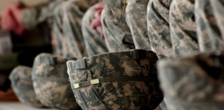 in the color photo you can see many soldiers' helmets lined up with the typical colors of the military style, and, behind them, the uniforms of the soldiers.